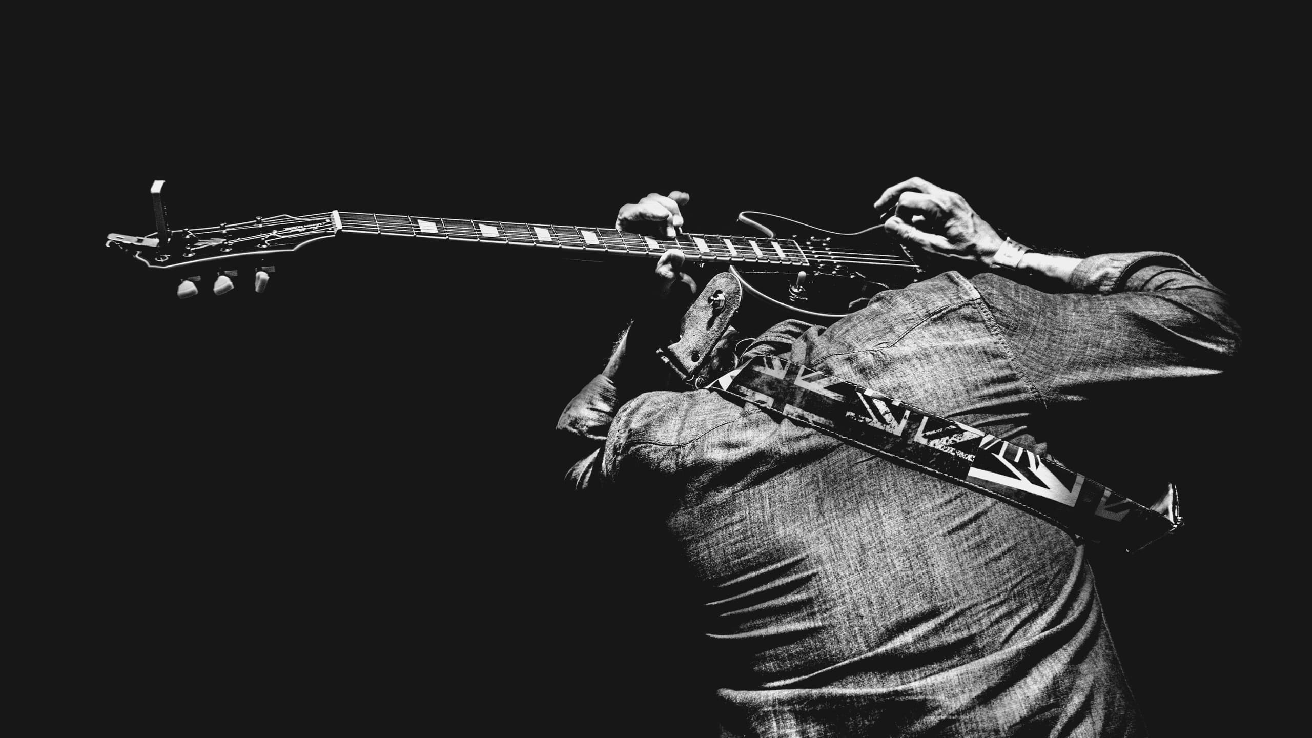 Man playing guitar behind his head