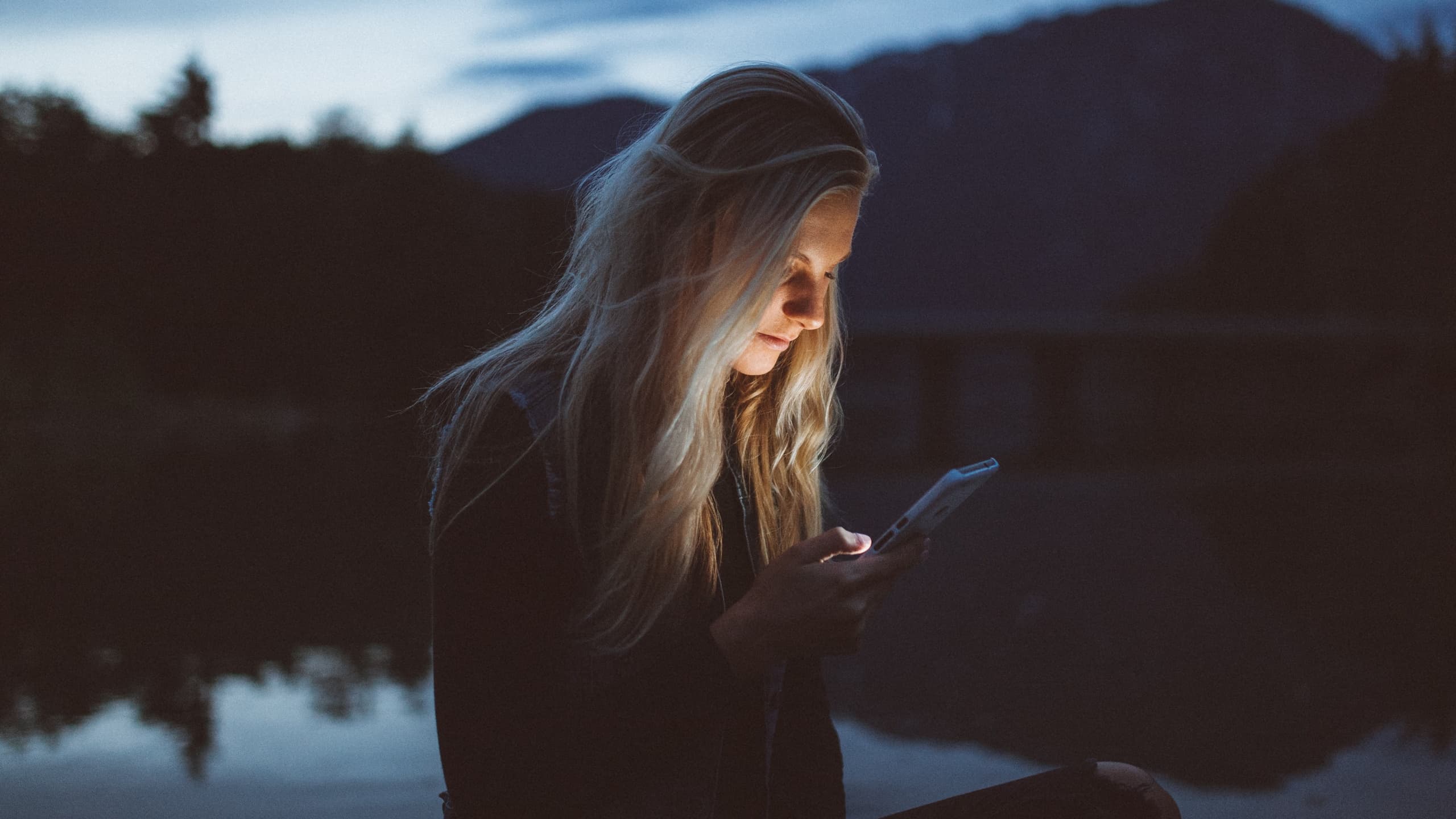 Woman staring at screen near lake