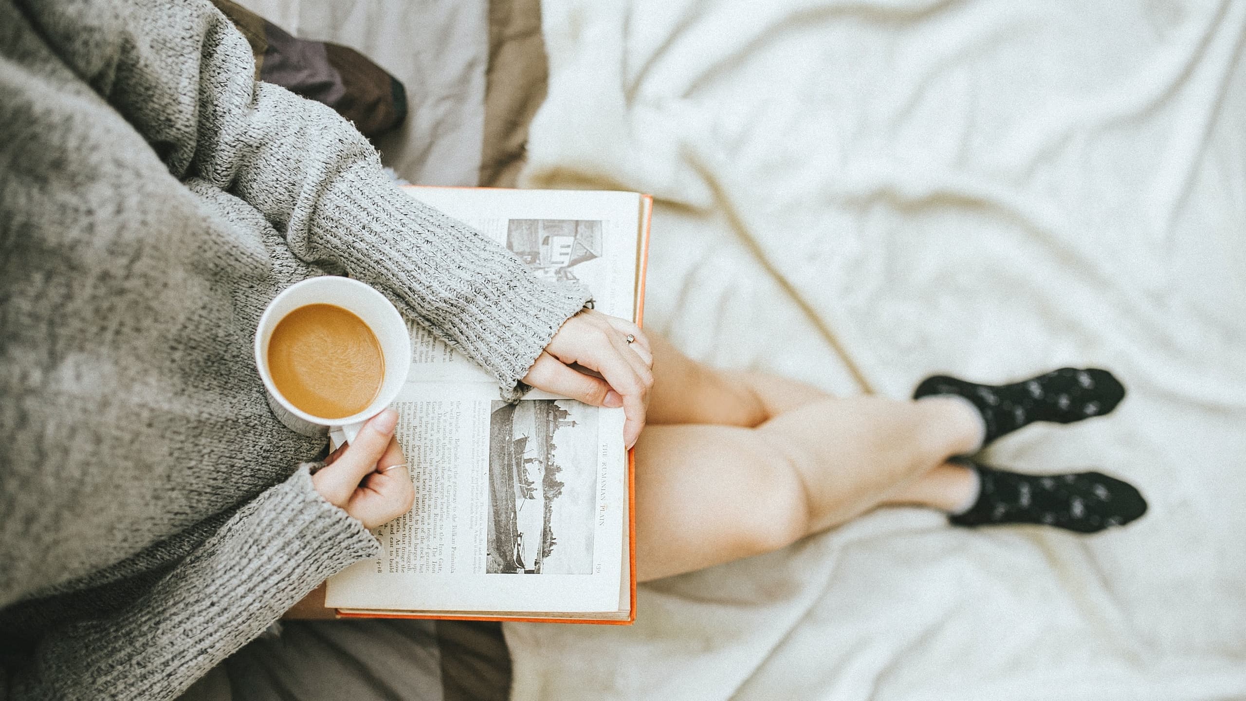 Woman sitting with coffee and book