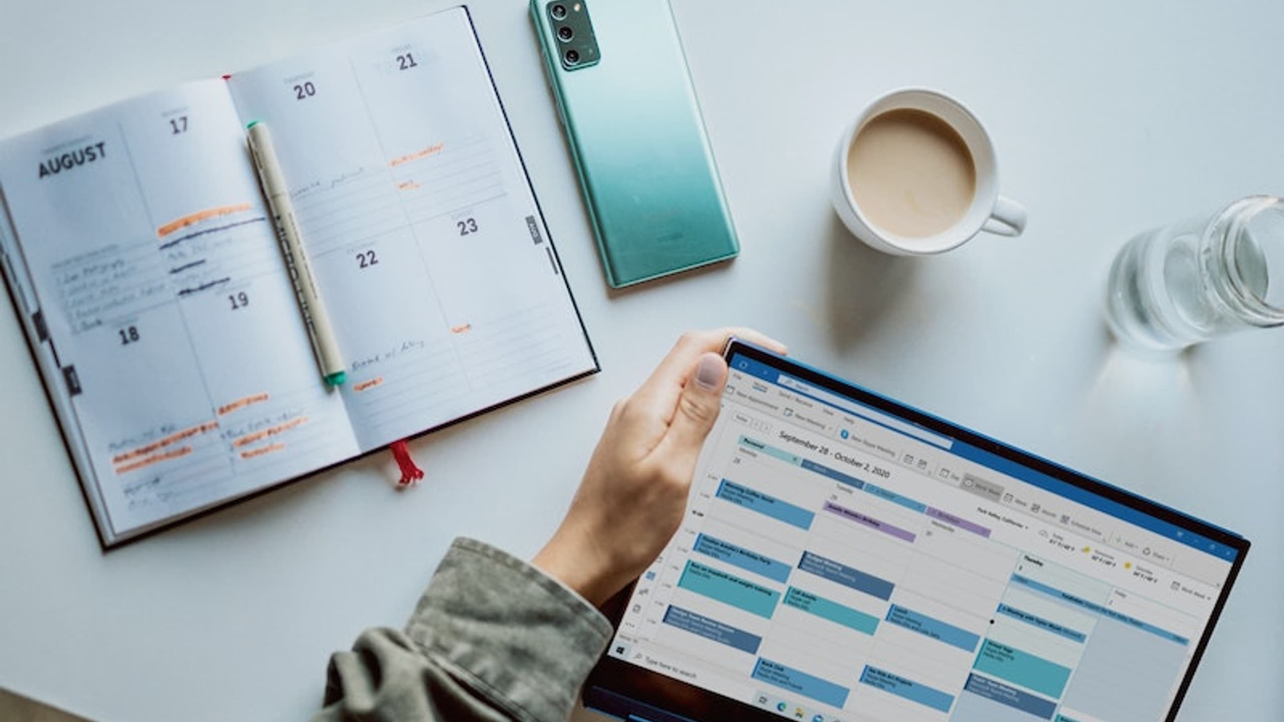 calendars on white table with coffee and glass of water
