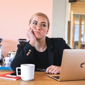 Woman staring into space and procrastinating in front of a laptop