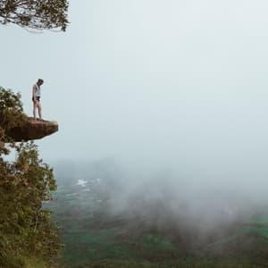 Woman standing on mountain looking into fog